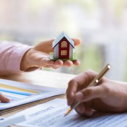 Real estate agent pointing at a document and walking a buyer through their home purchase contract.